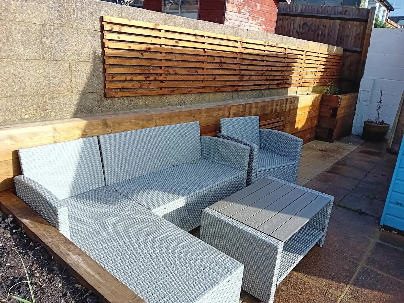 Contemporary outdoor seating area featuring rattan furniture and timber cladding, designed for relaxed garden entertaining.