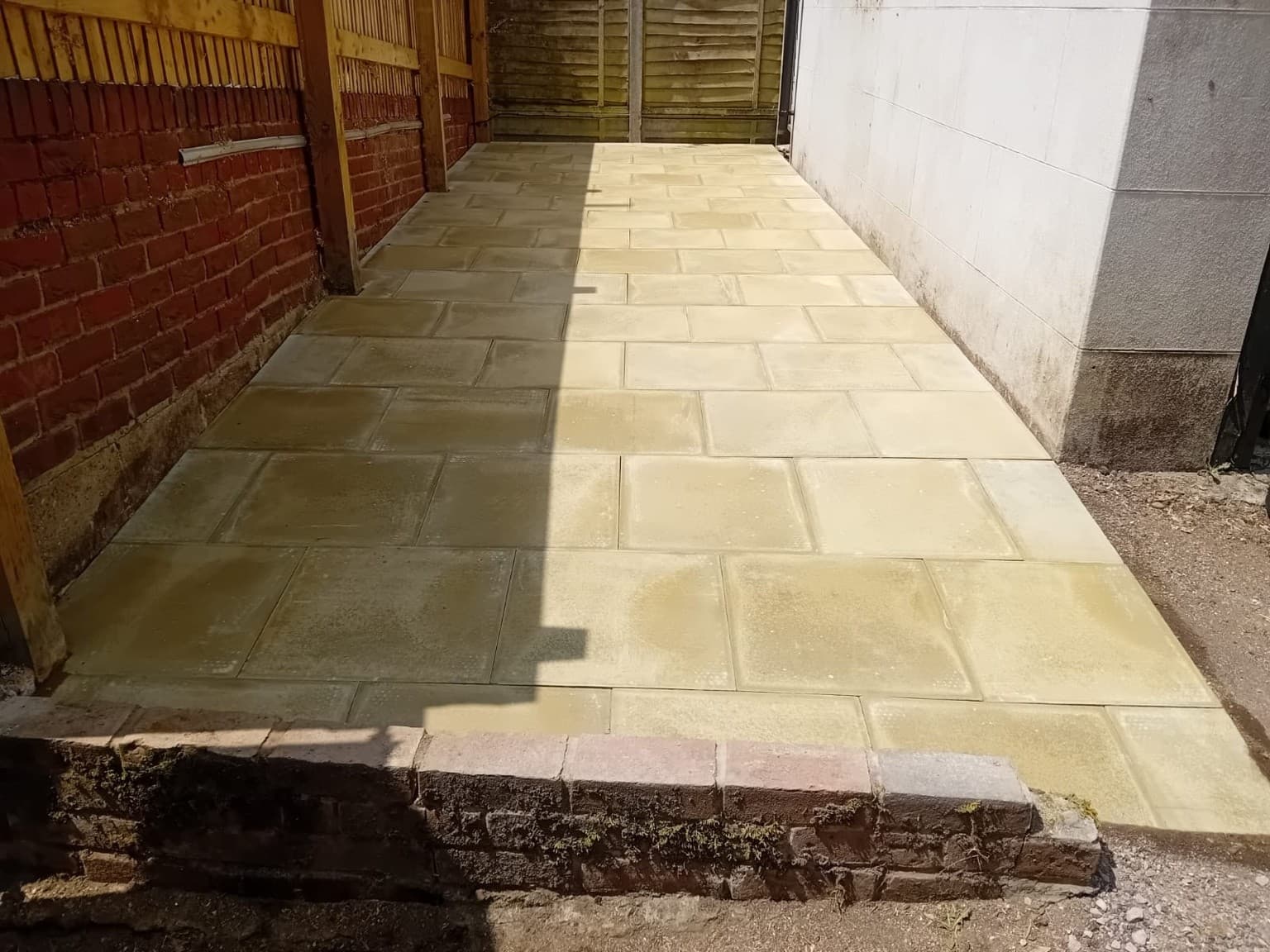 Newly installed sandstone patio with clean lines and level paving, completed as part of a professional garden hard-landscaping project.