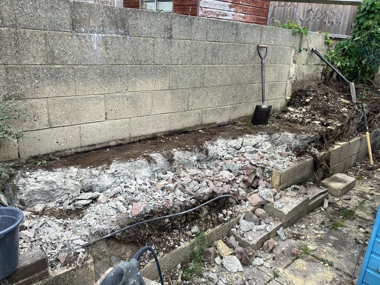 Before – uneven terraced area with old concrete and retaining wall prior to new seating area installation in a Brighton garden.